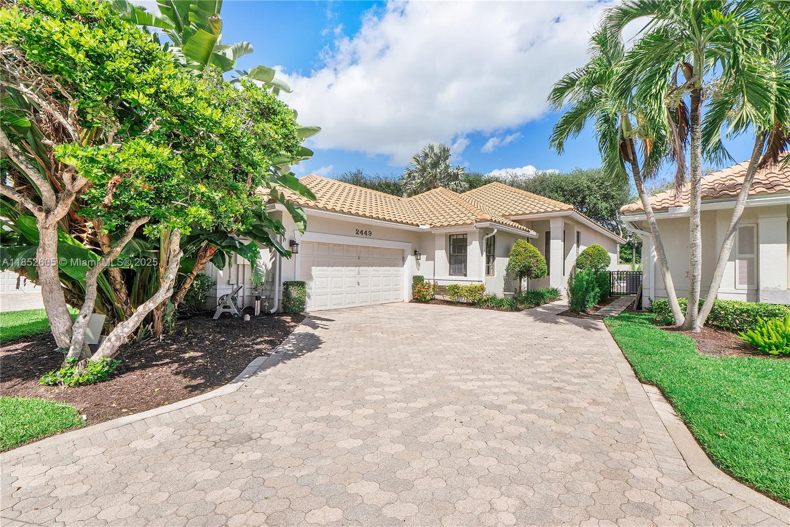 A single-story house with a tiled roof, a paved driveway, and lush tropical landscaping — 2449 NW 64th St, Boca Raton FL 33496, BOCA RATON, FL
