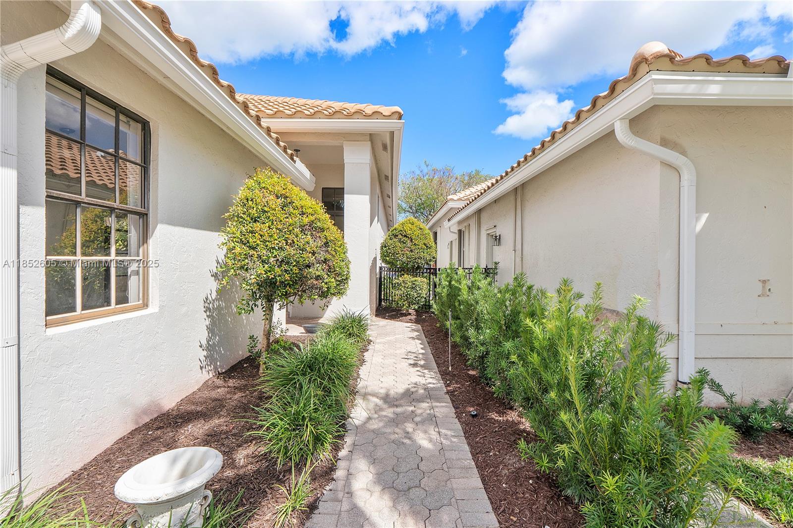 A paved walkway leads between two stucco houses with tiled roofs and landscaped garden beds — 2449 NW 64th St, Boca Raton FL 33496, BOCA RATON, FL