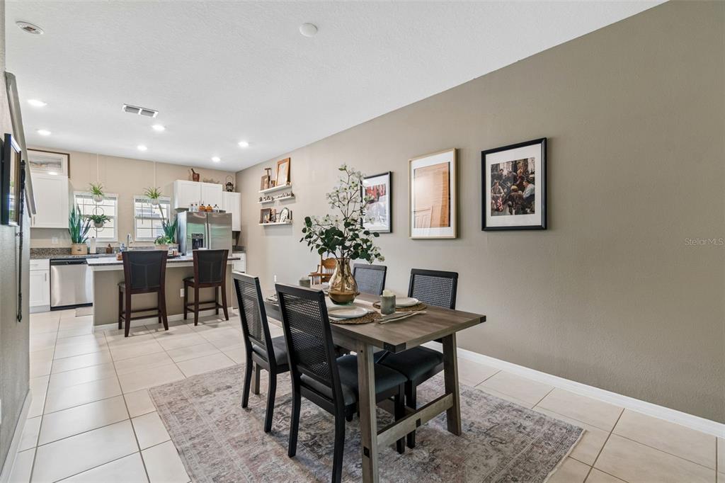 A dining area with a table and chairs leads into a kitchen with white cabinets — 852 TENNYSON MILL CIRCLE, TAMPA, FL