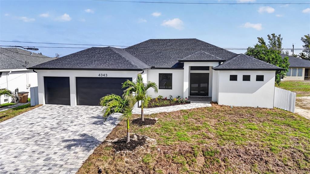 A modern single-story house with a white exterior, dark roof, and a paved driveway — 4343 NW 31ST TERRACE, CAPE CORAL, FL