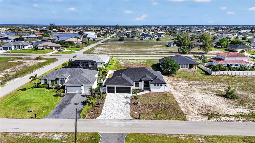 An aerial view shows two modern suburban houses with paved driveways and surrounding vacant lots — 4343 NW 31ST TERRACE, CAPE CORAL, FL