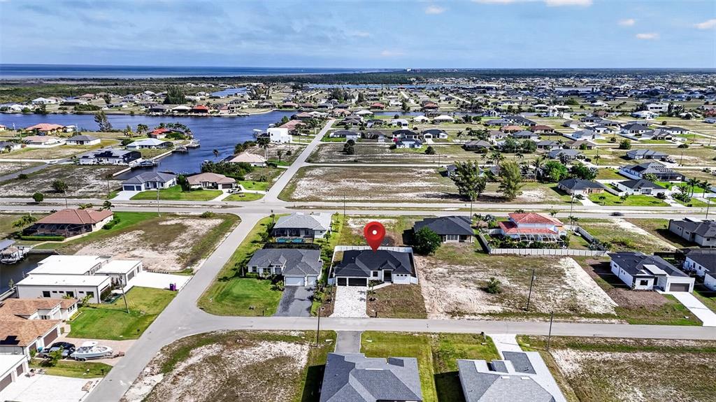 An aerial view shows a modern house with a red map pin in a residential neighborhood — 4343 NW 31ST TERRACE, CAPE CORAL, FL