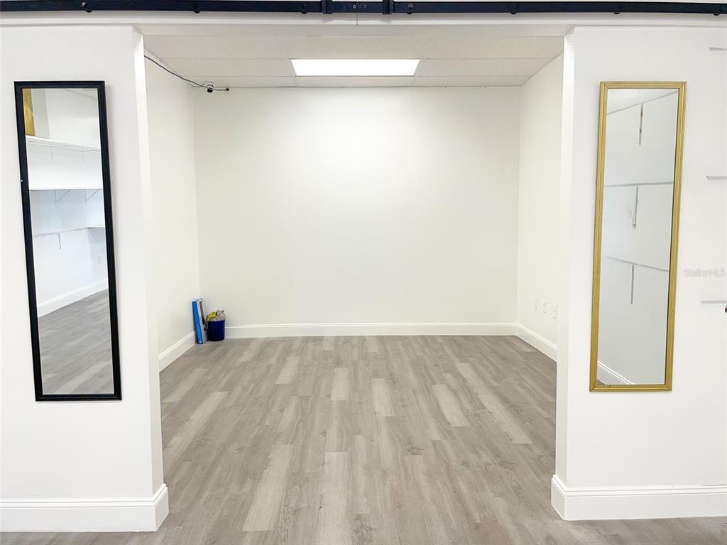 A room with light wood-look flooring, white walls, and two mirrors mounted on the walls — 5508 US HIGHWAY 98 N, LAKELAND, FL