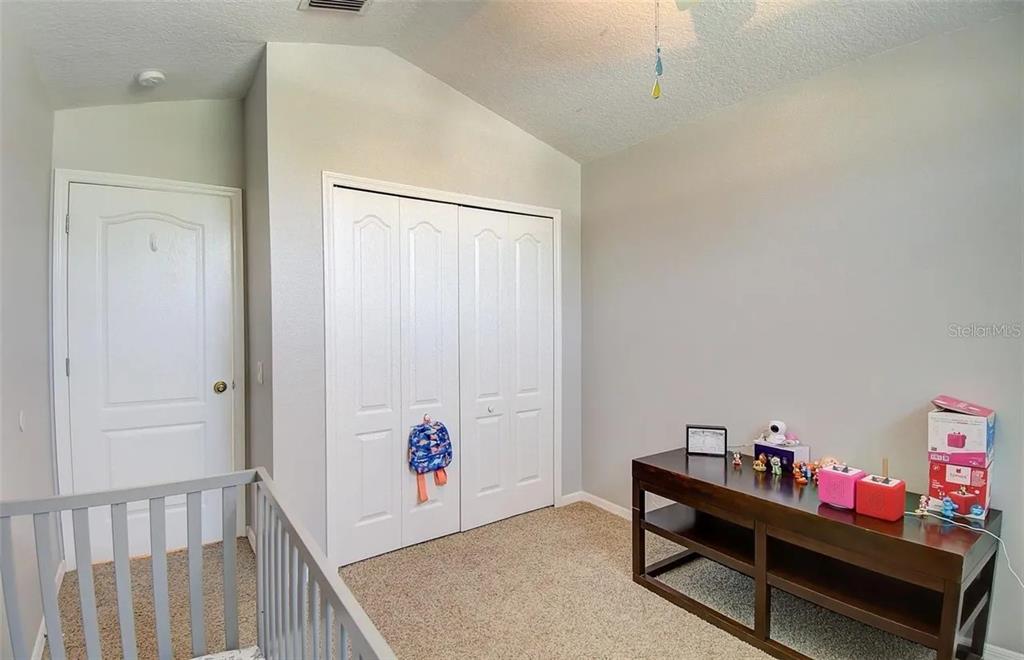 A tan house with a screened-in back porch sits on a large, grassy lawn — 3137 CASTLE ROCK CIRCLE, LAND O LAKES, FL