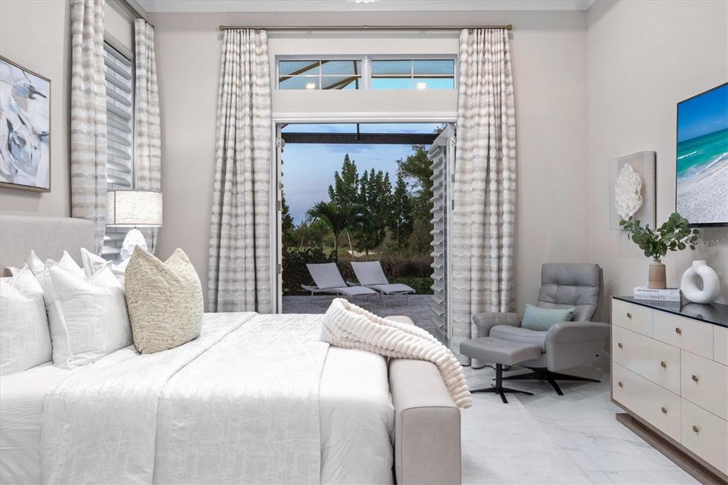 A bright bedroom features a king bed, a gray armchair, and glass doors opening outdoors — 8352 SEA GLASS COURT, SARASOTA, FL