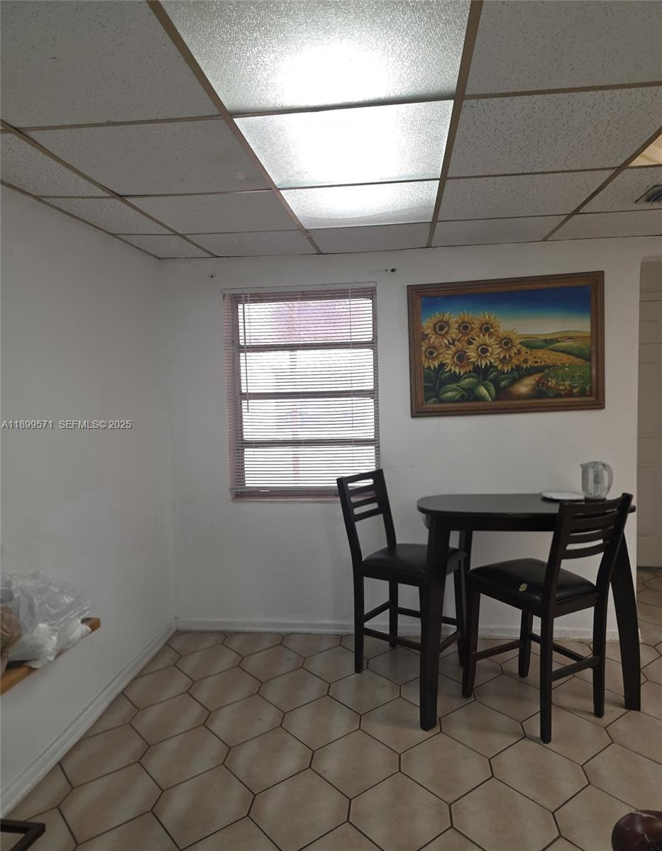 A small dining area features a dark wood table, two chairs, and a sunflower painting — 250 NW 63rd Ct, Miami FL 33126, MIAMI, FL