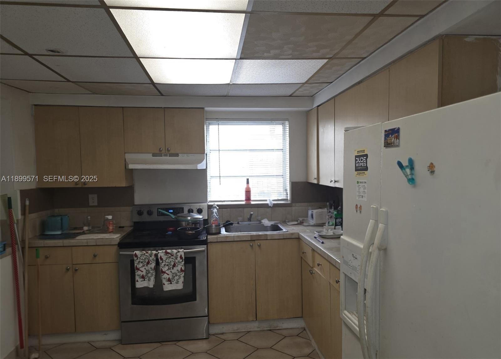 A kitchen features light wood cabinets, a stainless steel stove, and a white refrigerator — 250 NW 63rd Ct, Miami FL 33126, MIAMI, FL