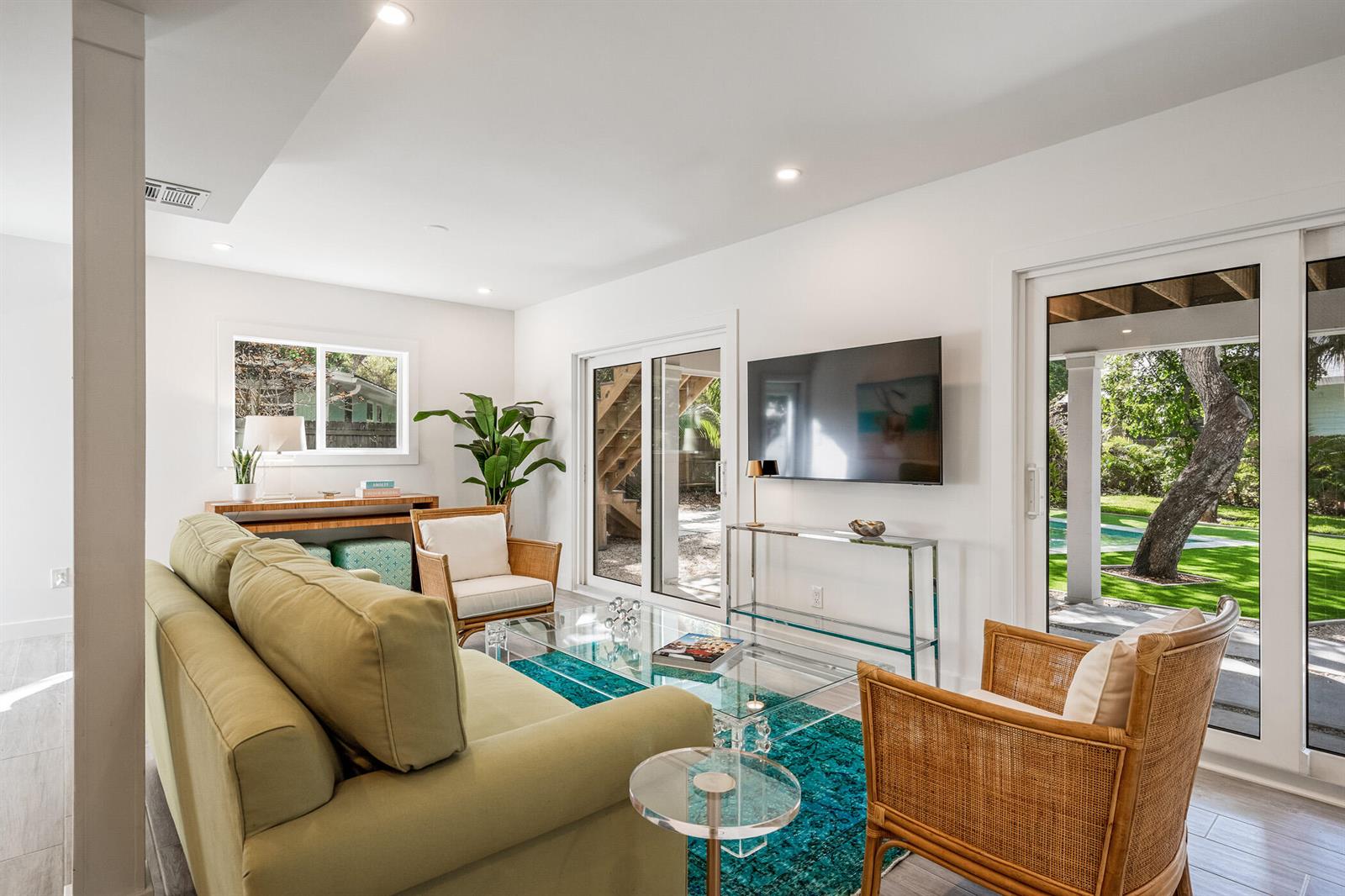 A living room with a green sofa, rattan chairs, glass tables, and sliding glass doors — 1881 E Pebble Path, Vero Beach FL 32963, VERO BEACH, FL