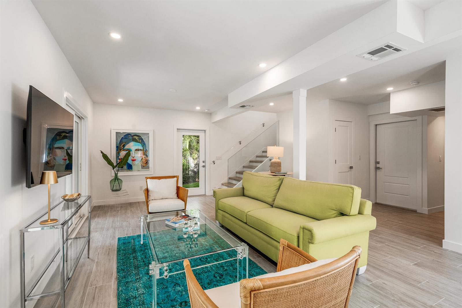 A living room features a green sofa, two rattan chairs, a glass coffee table, and stairs — 1881 E Pebble Path, Vero Beach FL 32963, VERO BEACH, FL