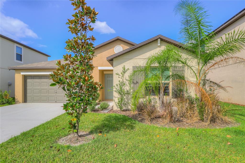 A single-story house with a tan stucco exterior, a garage, and a front yard — 8694 PARSONS HILL BOULEVARD, WESLEY CHAPEL, FL