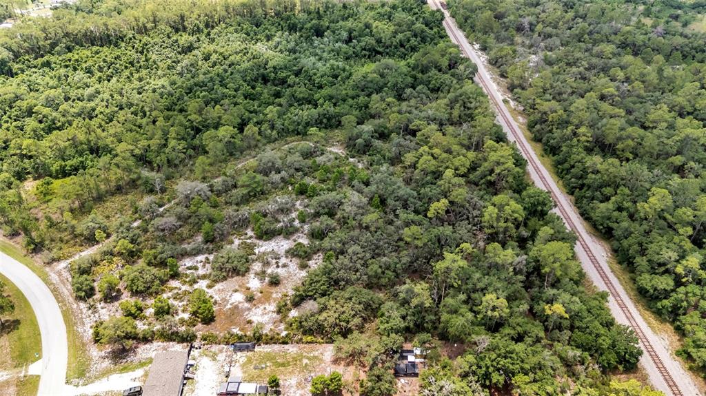 An aerial view shows a wooded lot adjacent to a railroad track and a paved road — WOODSTORK WAY, FROSTPROOF, FL