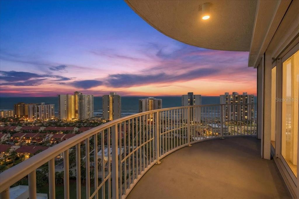 A curved balcony overlooks a coastal cityscape and ocean at sunset — 2 OCEANS WEST BOULEVARD UNIT 2006, DAYTONA BEACH, FL