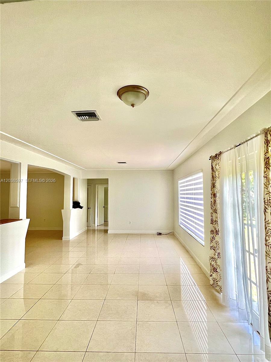 A bright, tiled living area features a ceiling light fixture and sliding glass patio doors — 1506 Delgado Ave, Coral Gables FL 33146, CORAL GABLES, FL