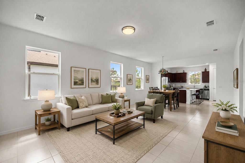 A living room with tile flooring, a beige sofa, and an open kitchen in the background — 9412 SW 53RD PLACE, OCALA, FL