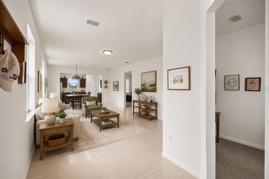 A bright living room with tile floors flows into a dining area with dark wood furniture — 9412 SW 53RD PLACE, OCALA, FL