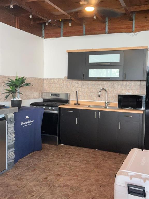 An outdoor kitchen features dark cabinets, a stainless steel stove, and a tiled backsplash — 119 CARR 119 BO POZAS, SAN SEBASTIAN, PR
