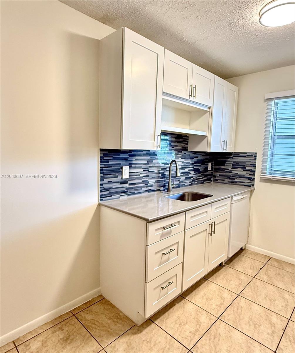 A kitchen features white shaker cabinets, a blue mosaic tile backsplash, and light-colored countertops — 30 SE 4th Ave # 206, Hallandale Beach FL 33009, HALLANDALE BEACH, FL