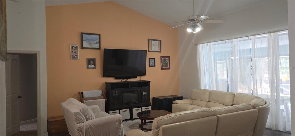 A living room features a vaulted ceiling, a large television, and a sectional sofa — 27 GRASS STREET, HOMOSASSA, FL