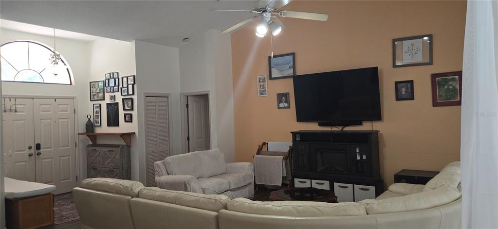 A living room features a vaulted ceiling, a large television, and a light-colored sectional sofa — 27 GRASS STREET, HOMOSASSA, FL