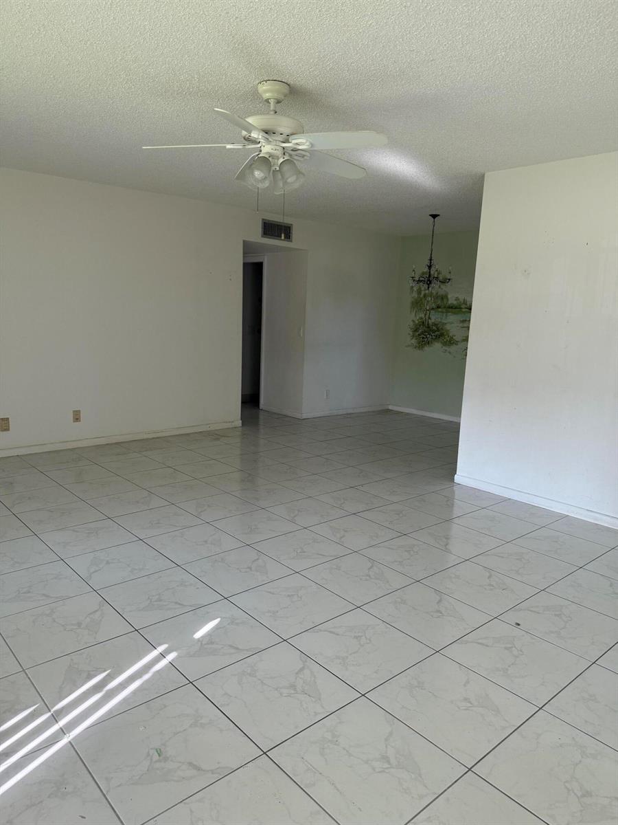 An empty room with white tile floors, a ceiling fan, and a mural on the wall — 211 Country Lane # A, Boynton Beach FL 33435, BOYNTON BEACH, FL