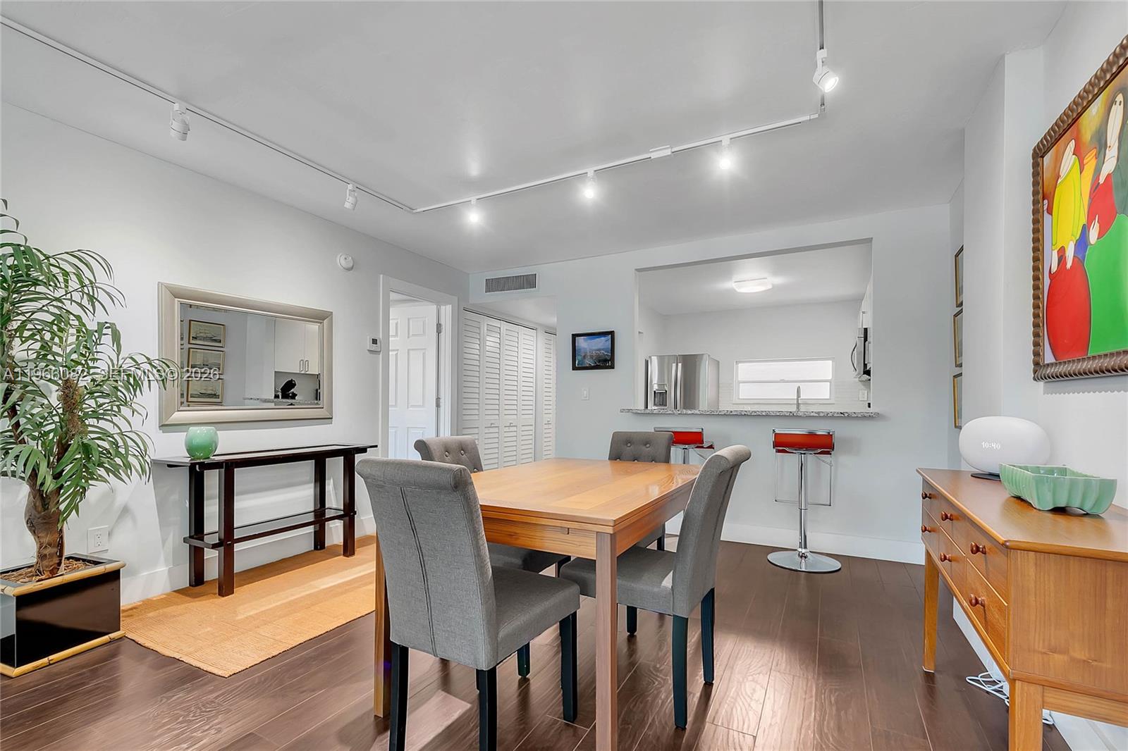 A dining room with a wooden table, gray chairs, and an open kitchen pass-through — 100 Ocean Lane Dr # 202, Key Biscayne FL 33149, KEY BISCAYNE, FL