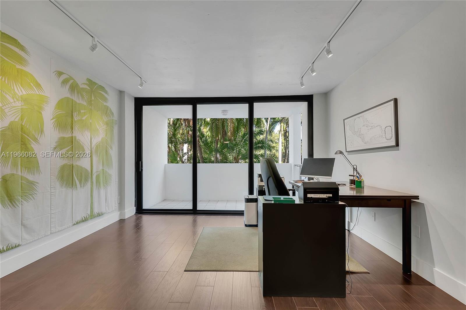 A home office features dark wood flooring, a desk, track lighting, and a sliding glass door — 100 Ocean Lane Dr # 202, Key Biscayne FL 33149, KEY BISCAYNE, FL