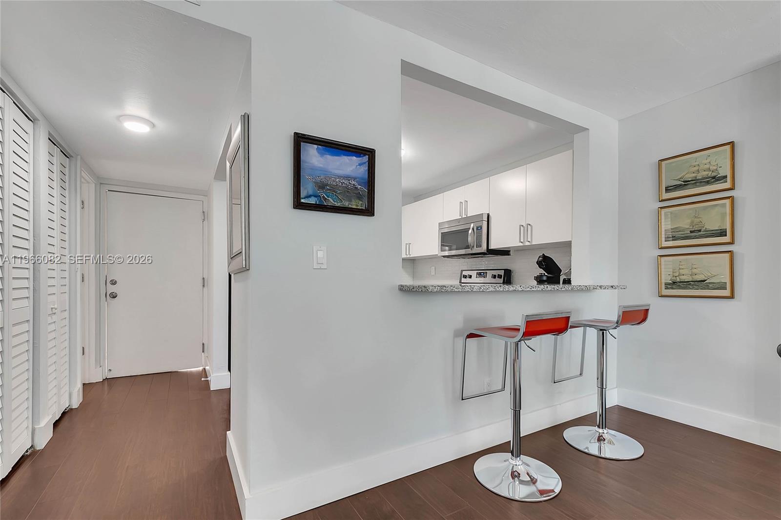 A kitchen pass-through window overlooks a dining area with two red bar stools — 100 Ocean Lane Dr # 202, Key Biscayne FL 33149, KEY BISCAYNE, FL