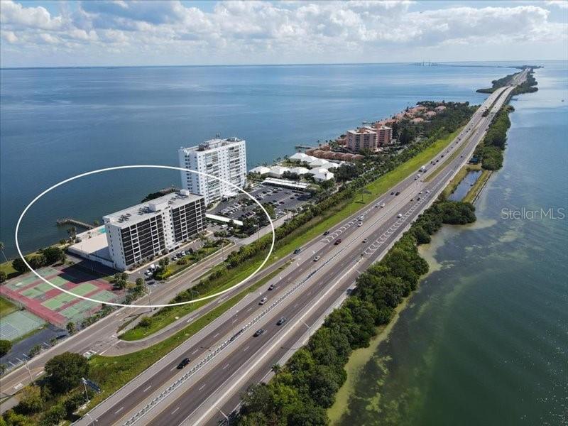 An aerial view shows a multi-story residential building circled next to a coastal highway — 7100 SUNSHINE SKYWAY LANE S UNIT 706, ST PETERSBURG, FL
