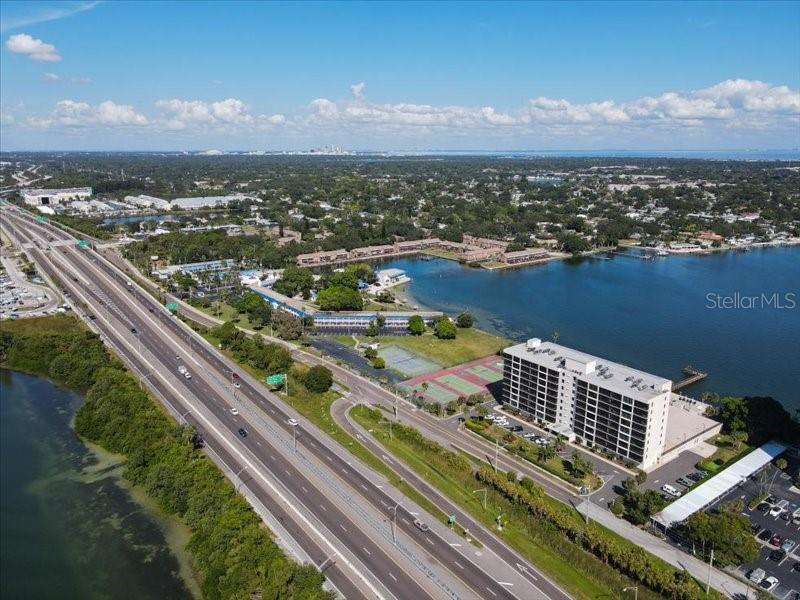 An aerial view shows a multi-story apartment building next to a highway and a lake — 7100 SUNSHINE SKYWAY LANE S UNIT 706, ST PETERSBURG, FL