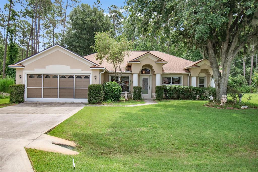 A single-story house with a beige stucco exterior, a two-car garage, and a front lawn — 17 EBB TIDE DRIVE, PALM COAST, FL