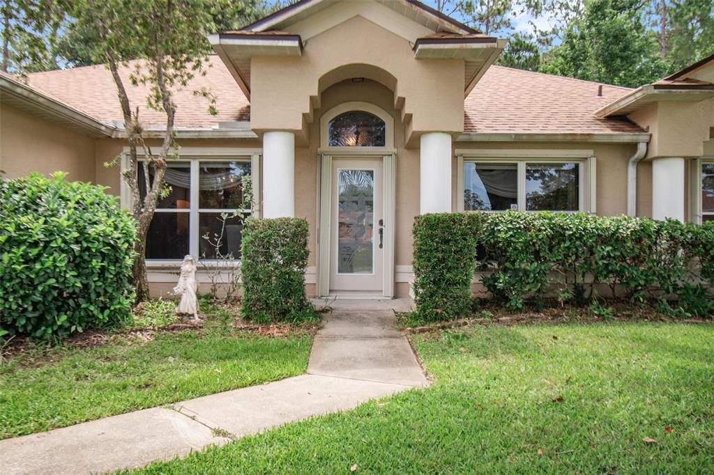 The front exterior of a tan house features a covered entryway with two white columns — 17 EBB TIDE DRIVE, PALM COAST, FL