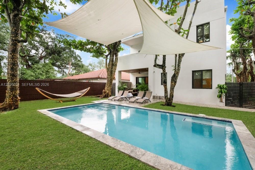A backyard features a rectangular swimming pool, lounge chairs, a hammock, and a shade sail — 3379 William Ave, Miami FL 33133, MIAMI, FL