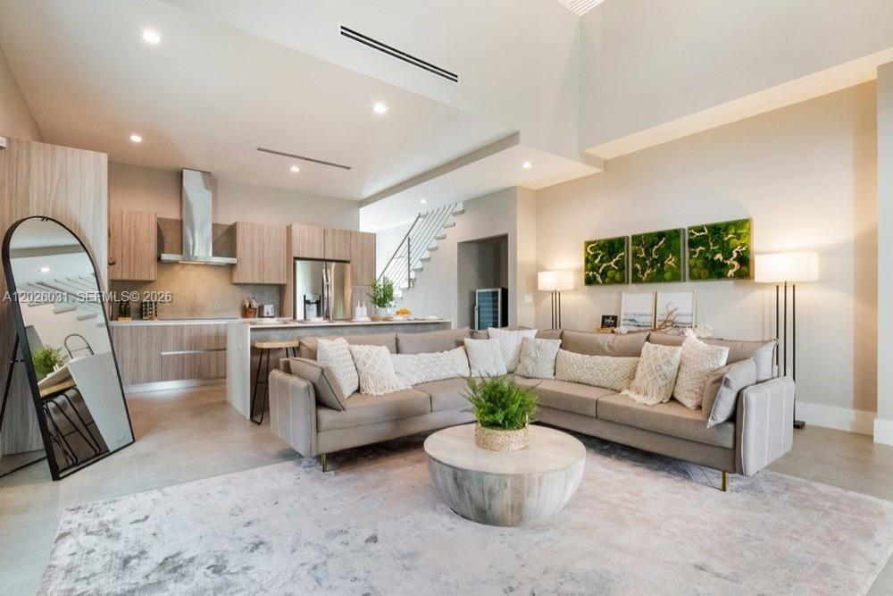 A modern open-concept living room features a sectional sofa, a round coffee table, and kitchen — 3379 William Ave, Miami FL 33133, MIAMI, FL