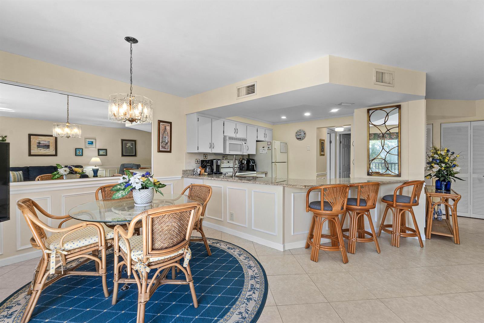A dining area and kitchen feature wicker furniture, a glass table, and a breakfast bar — 1605 S Us Highway 1 # D302, Jupiter FL 33477, JUPITER, FL
