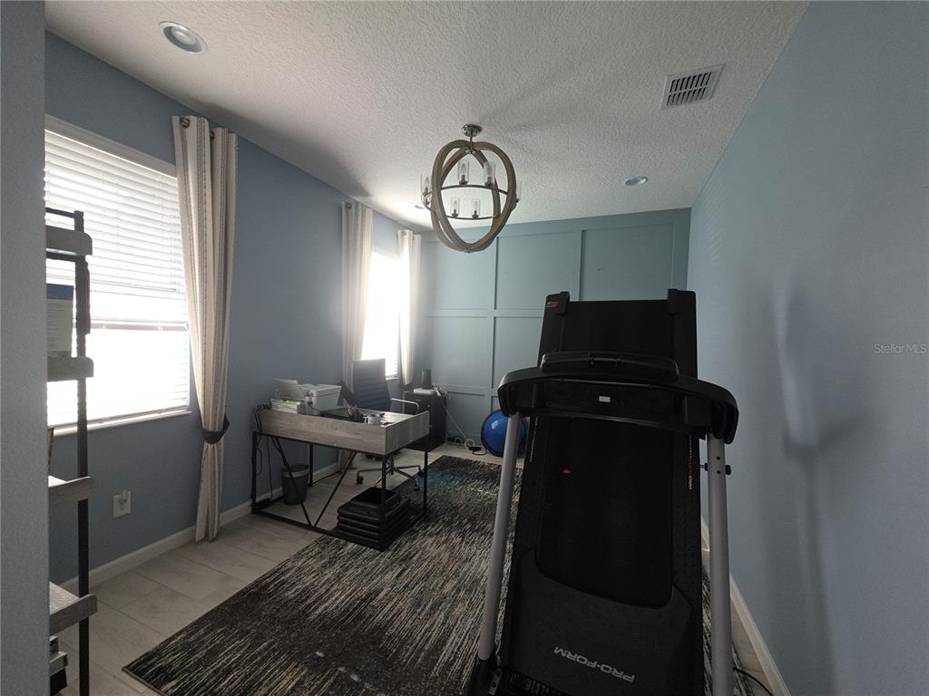 A hallway with light blue walls, tile flooring, a small white cabinet, and an open pantry — 958 COMPASS LANDING DRIVE, ORANGE CITY, FL