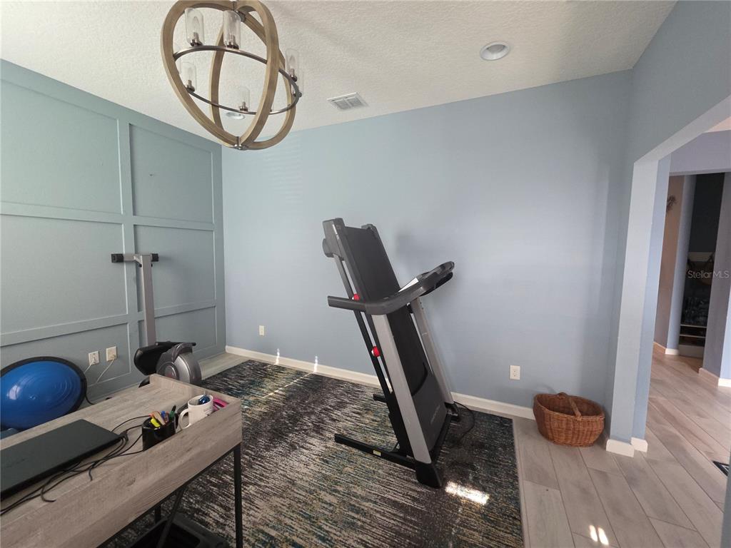 A kitchen features white cabinetry, a large island with bar seating, and light-colored tile flooring — 958 COMPASS LANDING DRIVE, ORANGE CITY, FL