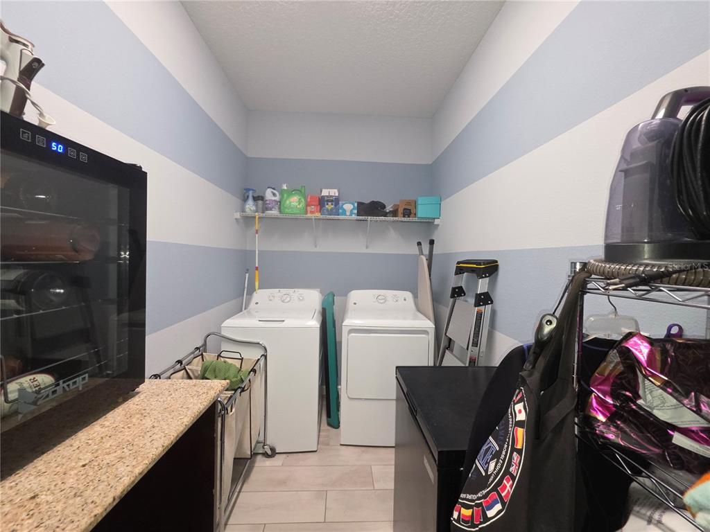A kitchen with white cabinets and an island opens into a living and dining area — 958 COMPASS LANDING DRIVE, ORANGE CITY, FL