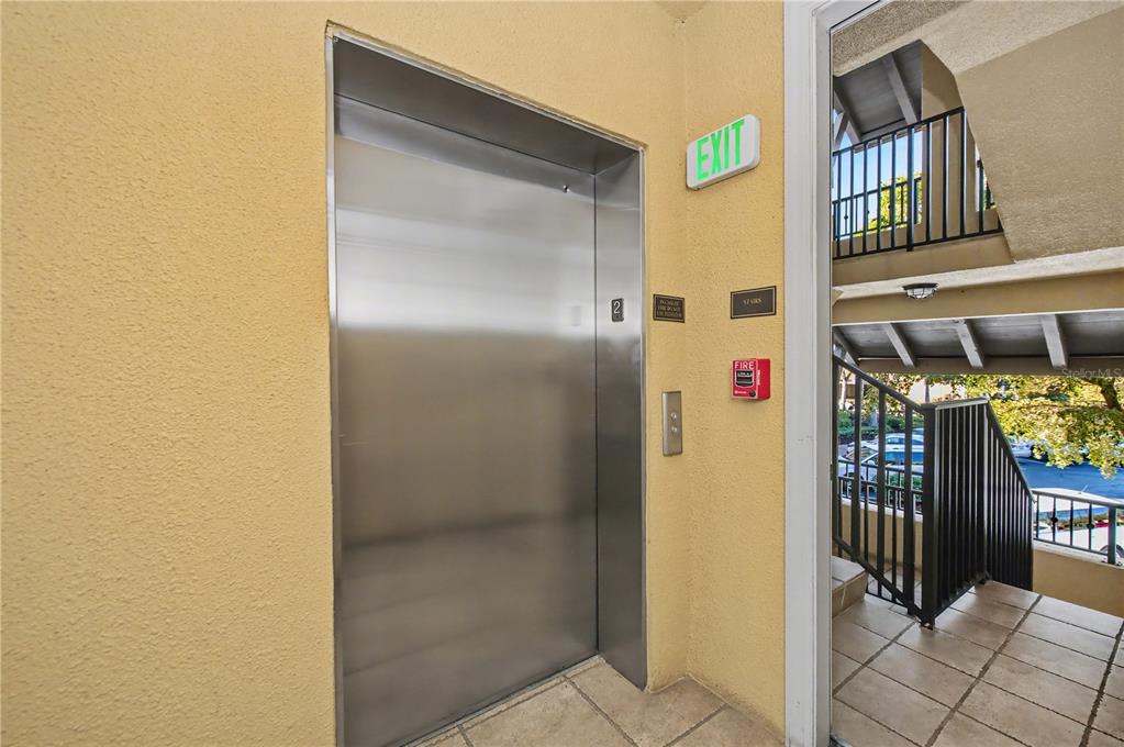 A stainless steel elevator door is located next to an open doorway leading to stairs — 96 VIVANTE BOULEVARD UNIT 24, PUNTA GORDA, FL