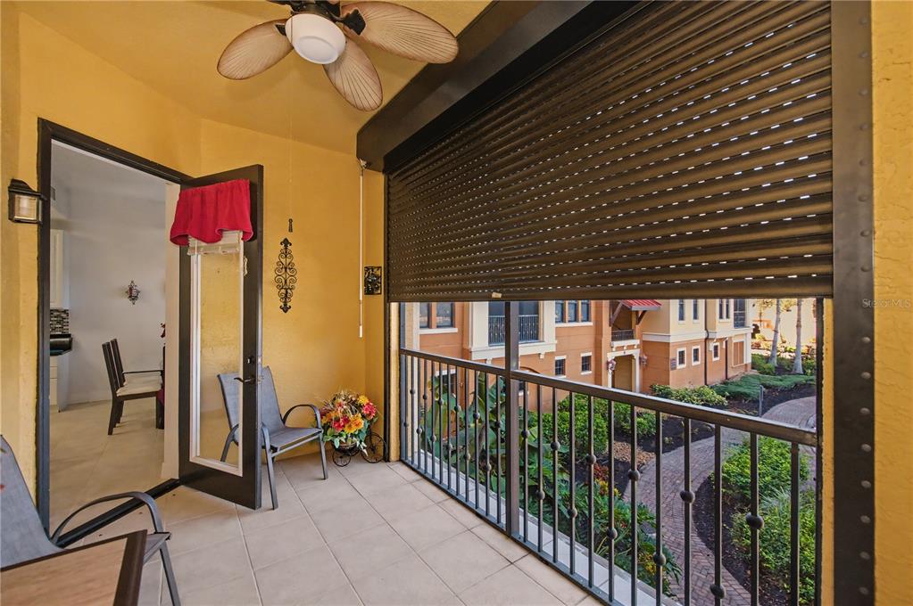 A covered balcony features tile flooring, a ceiling fan, and a retractable metal security shutter — 96 VIVANTE BOULEVARD UNIT 24, PUNTA GORDA, FL