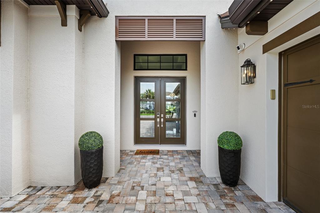 A front entryway features double glass doors, a paver floor, and two potted topiary plants — 34135 TOMPION WAY, WESLEY CHAPEL, FL
