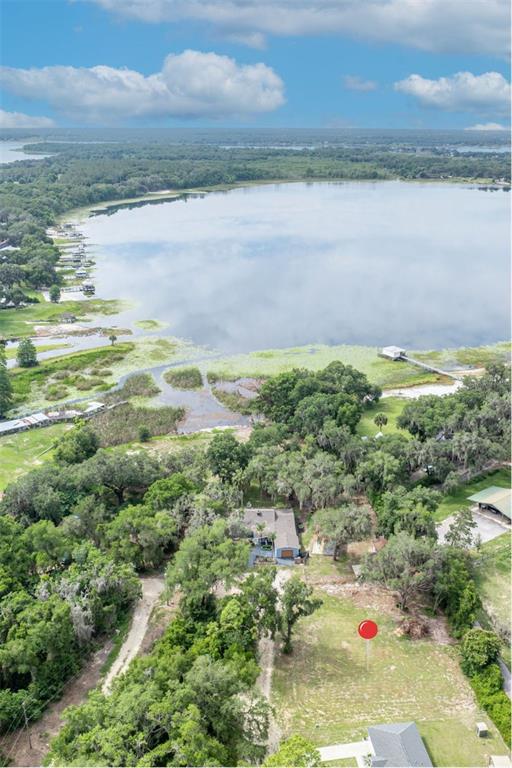An aerial view shows a house surrounded by trees near a large lake — SE 105TH TERRACE, OCKLAWAHA, FL