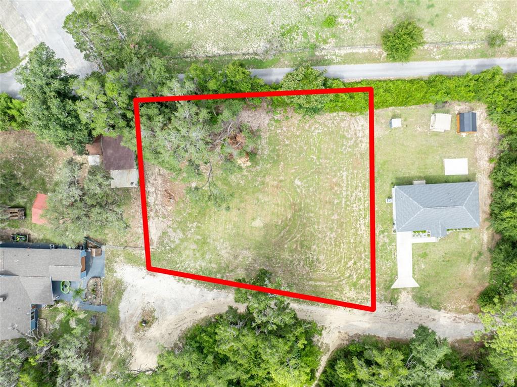 An aerial view shows a rectangular vacant lot outlined in red between two residential properties — SE 105TH TERRACE, OCKLAWAHA, FL