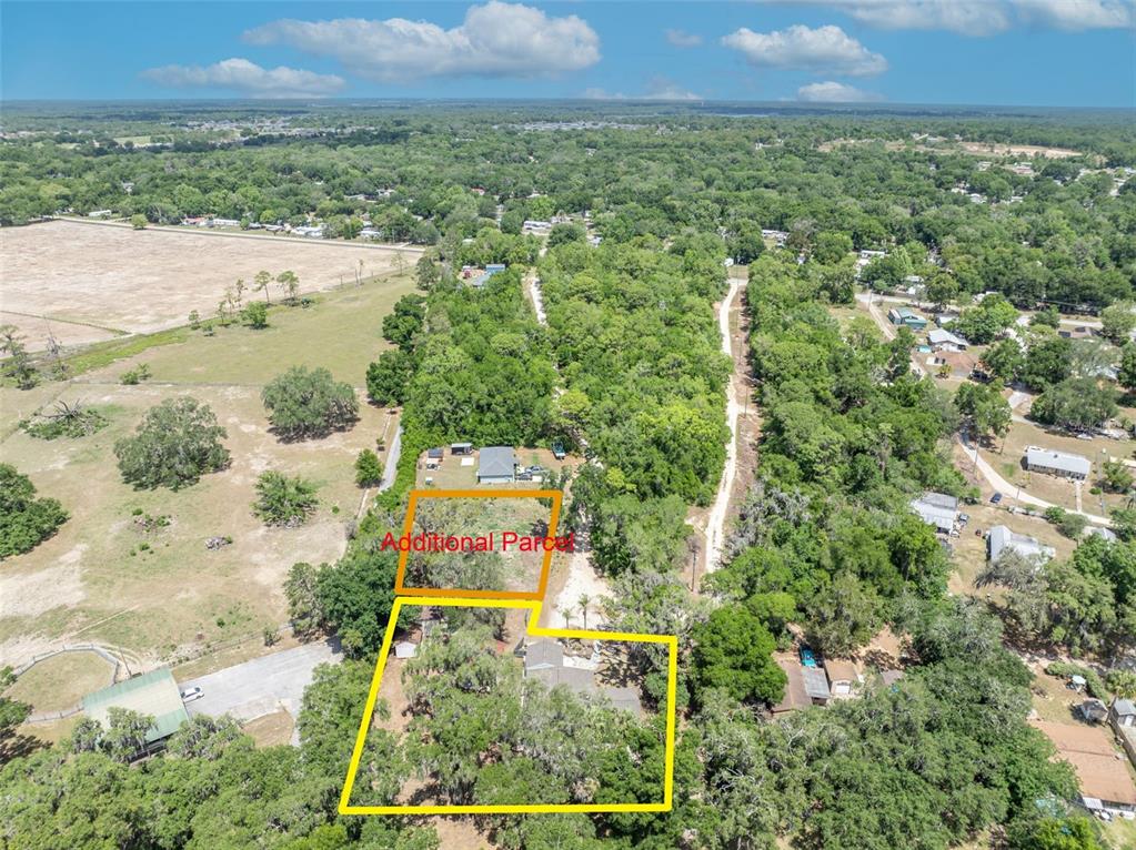 An aerial view shows two adjacent residential lots with trees and structures in a rural area — SE 105TH TERRACE, OCKLAWAHA, FL