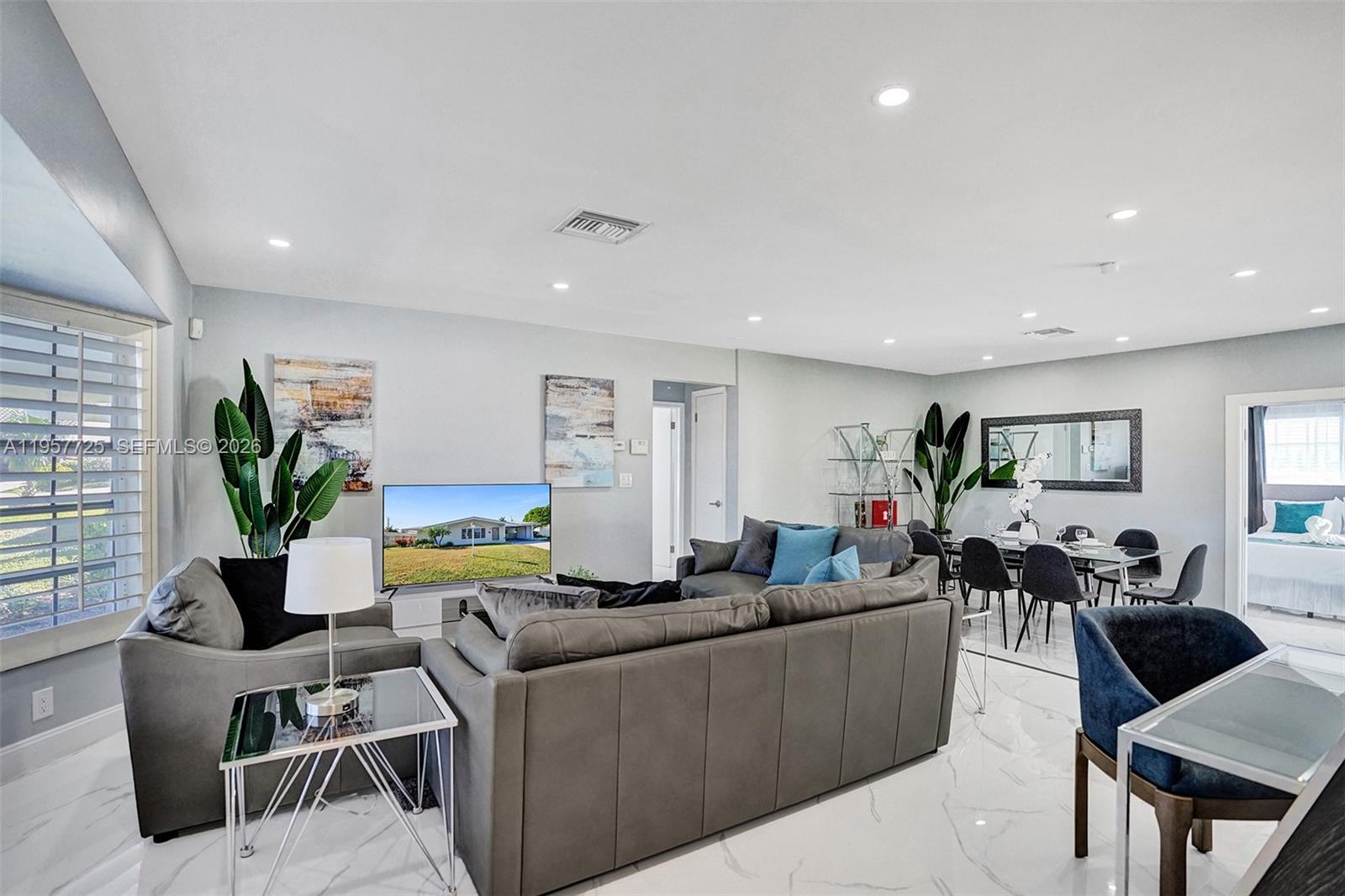 A living and dining area features gray leather sofas, white marble floors, and recessed lighting — 477 SE 17th Ter, Deerfield Beach FL 33441, DEERFIELD BEACH, FL