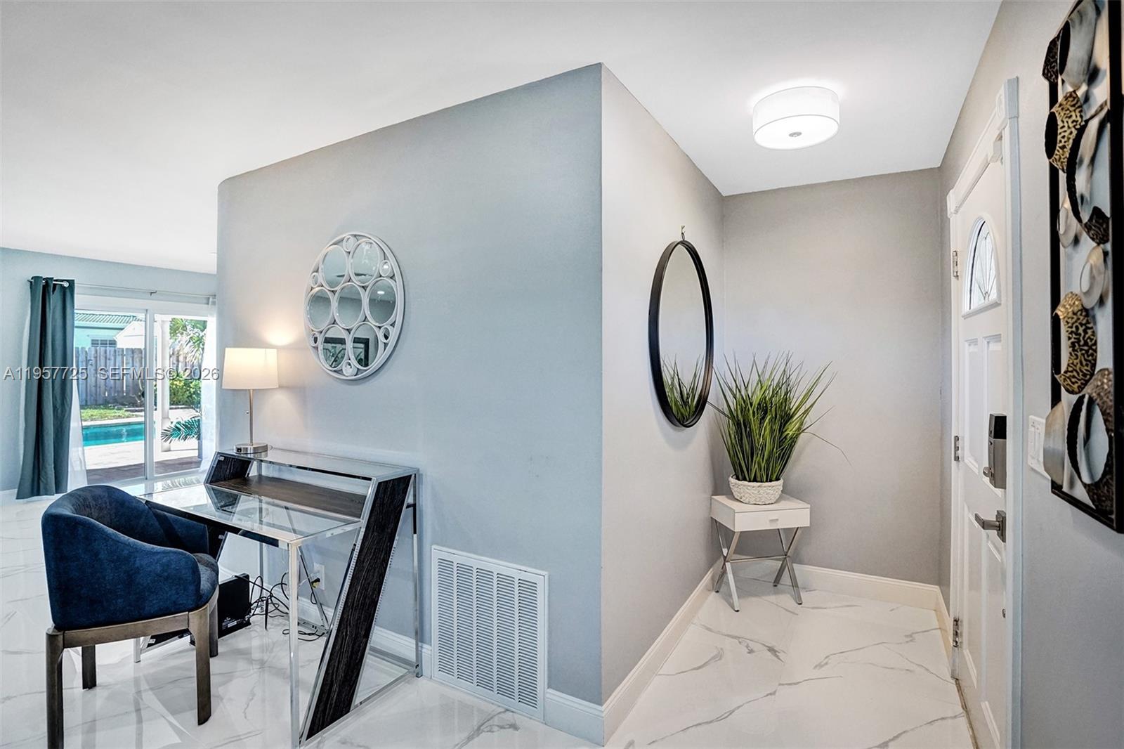 An entryway features a white door, a small table with a plant, and a desk area — 477 SE 17th Ter, Deerfield Beach FL 33441, DEERFIELD BEACH, FL
