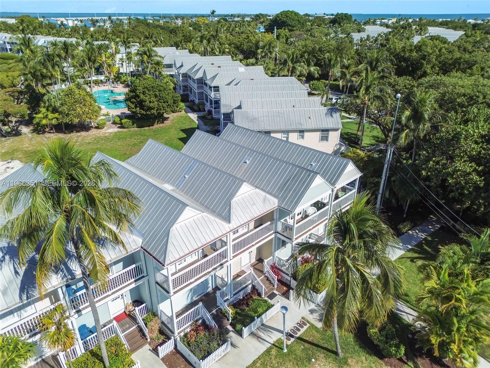 An aerial view shows a row of multi-story townhouses with metal roofs and palm trees — 5101 Sunset Village Dr, Duck FL 33050, DUCK, FL
