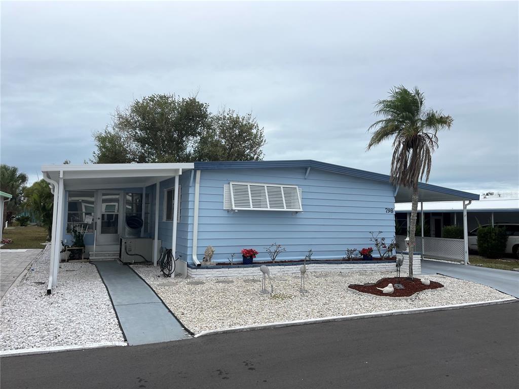 A light blue mobile home with a white roof, carport, and gravel landscaping — 798 GRADO DRIVE, VENICE, FL