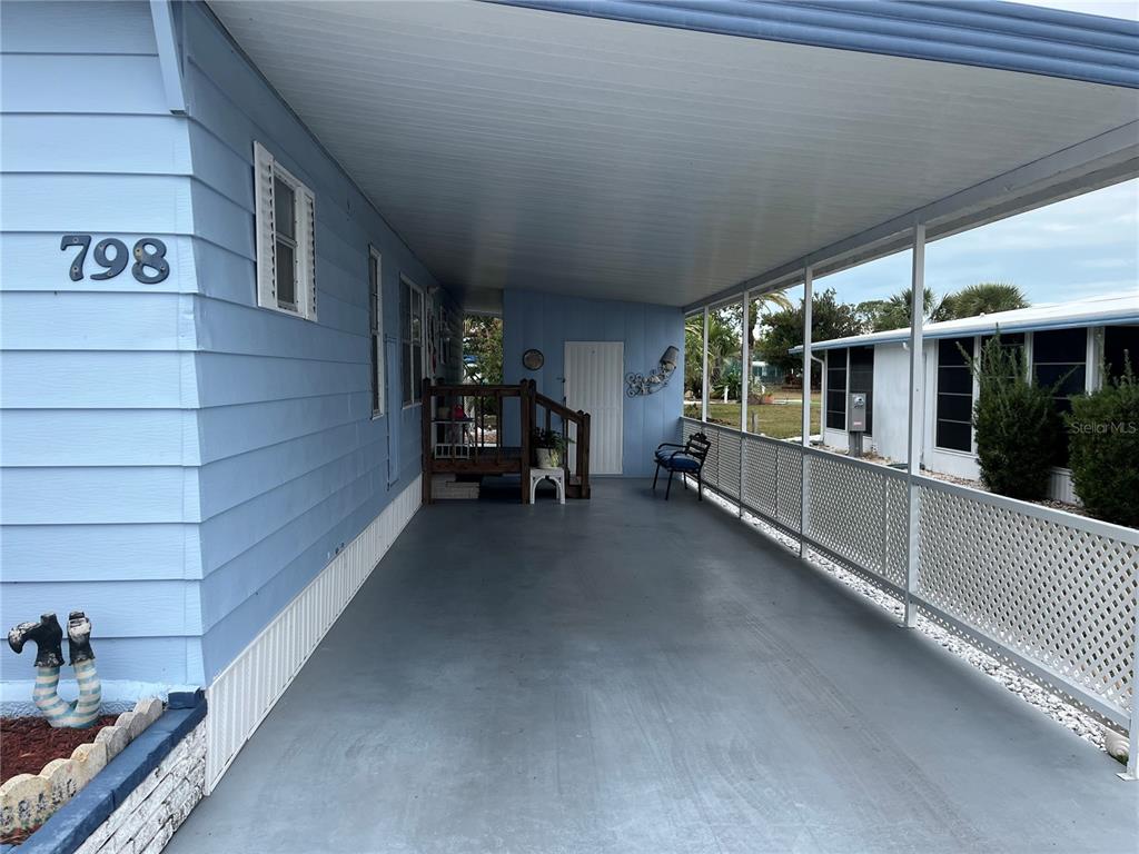 A covered carport with light blue siding, a white door, and a white lattice railing — 798 GRADO DRIVE, VENICE, FL