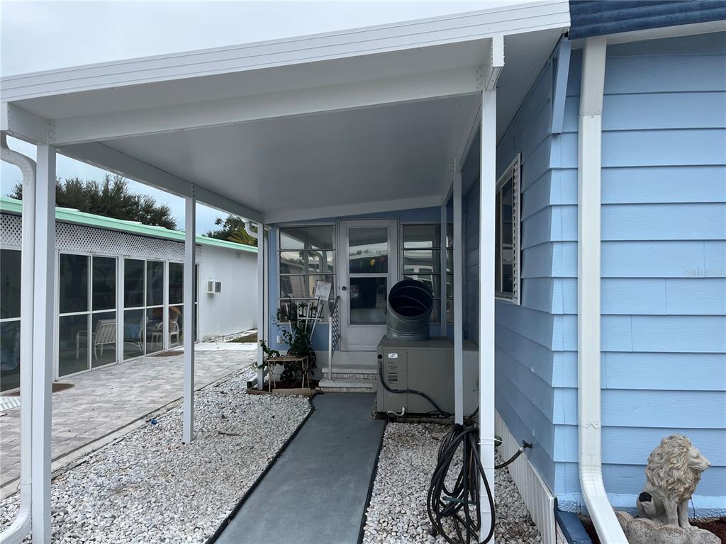 A blue mobile home features a covered entryway, a concrete walkway, and an outdoor HVAC unit — 798 GRADO DRIVE, VENICE, FL