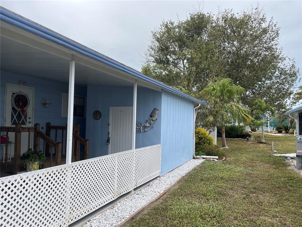 A light blue mobile home features a covered porch with white lattice skirting and siding — 798 GRADO DRIVE, VENICE, FL